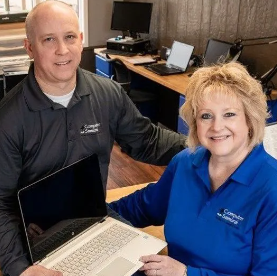 A man and woman holding a laptop computer.