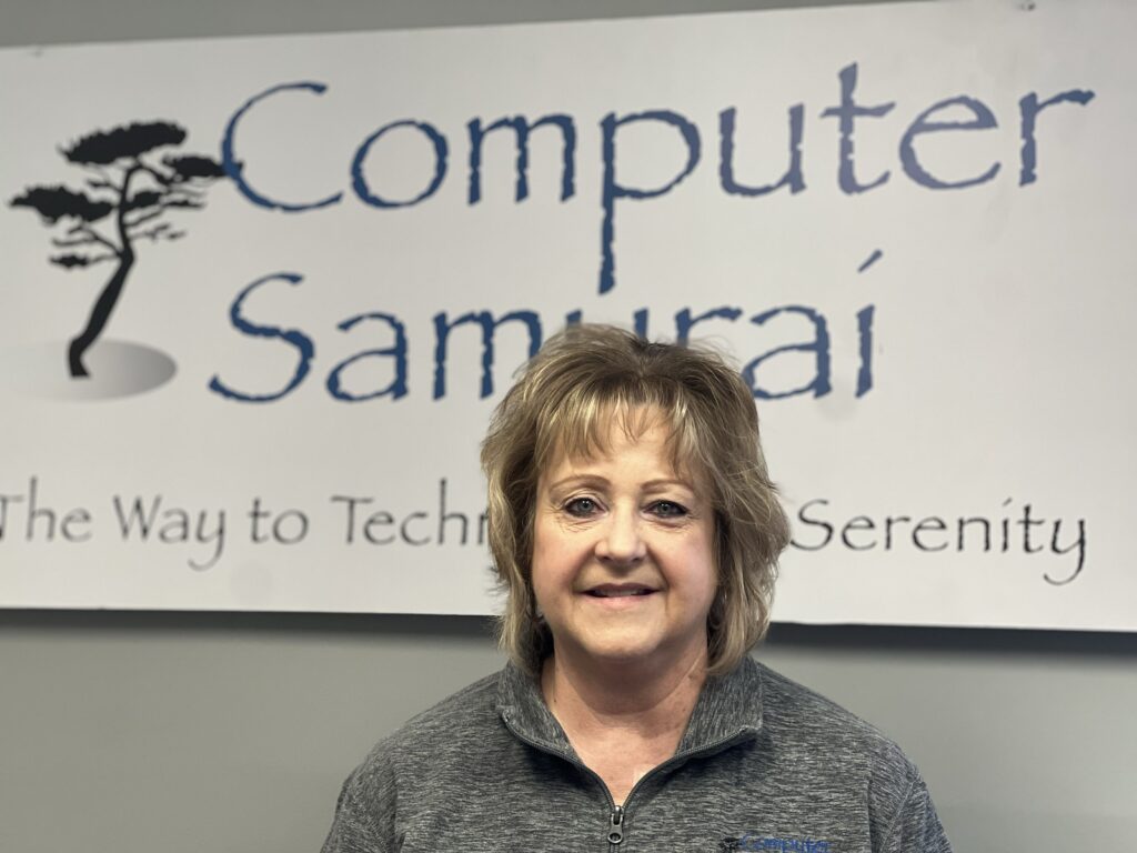 A woman standing in front of a computer samurai sign.