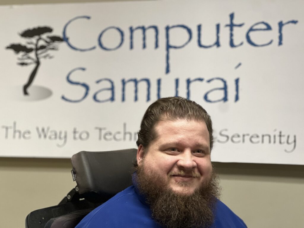 A man with long hair and beard sitting in a chair.