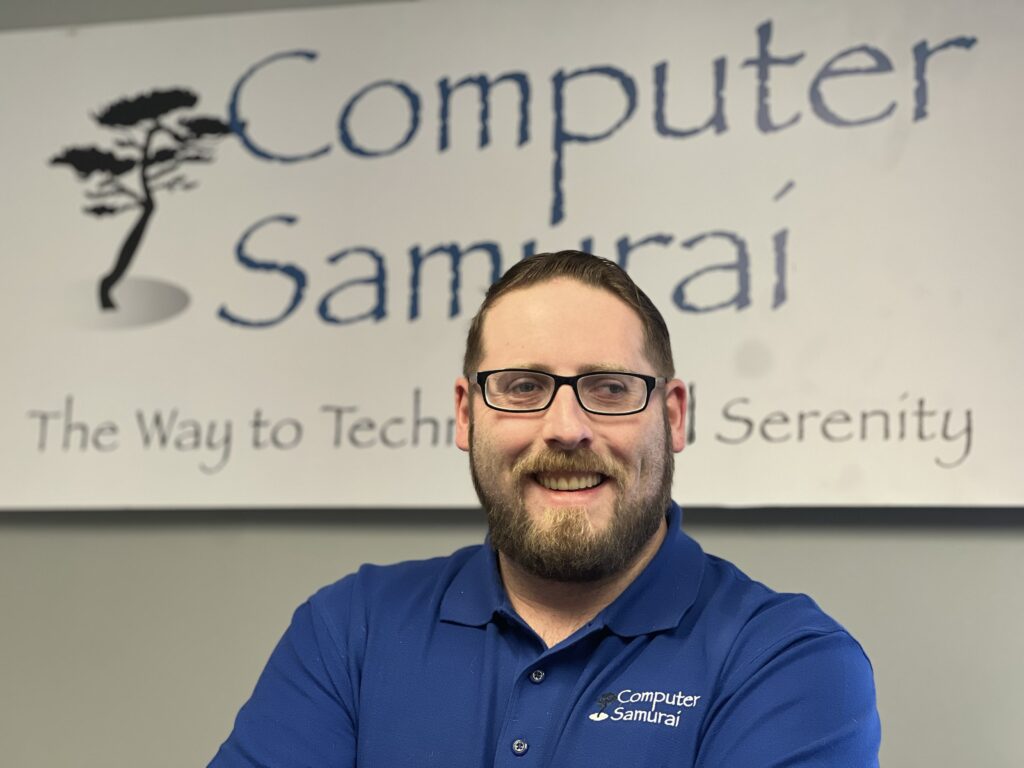 A man in front of a computer samurai sign.